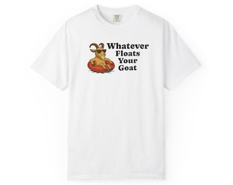 Puede incluir: Camiseta blanca con un dibujo de una cabra con gafas de sol en una boya roja. El texto "Whatever Floats Your Goat" está impreso en negro. La camiseta tiene cuello redondo y mangas cortas.