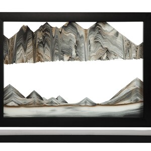 May include: A black sand art frame with a mountain scene. The sand is layered in shades of brown, gray, and white, creating a realistic mountain range.