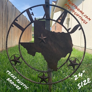 May include: A 24 inch metal Texas outline with a rope design and a rustic bronze finish. The outline is attached to a metal pole and is surrounded by green grass. The text "Texas Rustic Bronze" is written on the bottom left of the image and "24" Size is written on the bottom right.