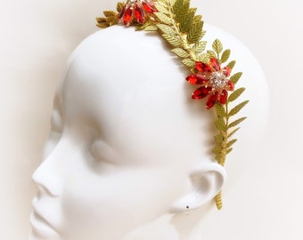 May include: A gold leaf headband with red and clear rhinestones. The headband is decorated with gold leaf branches and red flowers.