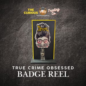 May include: A black badge reel with a yellow border, featuring a graphic of a woman with glasses and a yellow headband. The text "TRUE CRIME OBSESSED" is displayed below the graphic. The words "BADGE REEL" are at the bottom.
