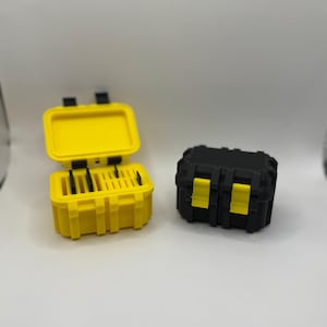 May include: Two small, plastic toolboxes. One is open and yellow, with black latches and interior dividers. The other is closed, black with yellow accents. Both have a rugged, industrial design.