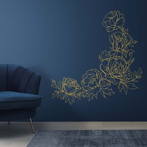 May include: A blue velvet armchair sits in front of a dark blue wall with a gold outline of a floral design.