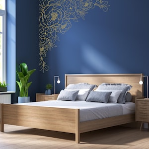 May include: A wooden bed frame with a light wood finish and a blue headboard. The bed has a white duvet and gray pillows. A gold floral design is on the wall behind the bed.