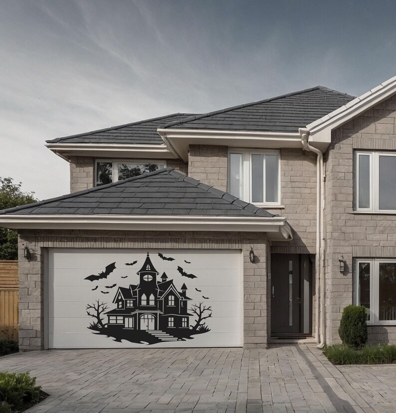 May include: A black silhouette of a haunted house with bats and trees is displayed on a white garage door. The house has multiple windows, turrets, and a central tower. The image is set against a backdrop of a brick house and a cloudy sky, perfect for Halloween.