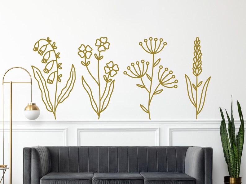 May include: Five gold outline floral designs on a white wall. The designs include a cluster of bell-shaped flowers, a cluster of small flowers, a cluster of small flowers with a larger flower at the top, a cluster of small flowers with a larger flower at the top, and a cluster of small flowers with a larger flower at the top.