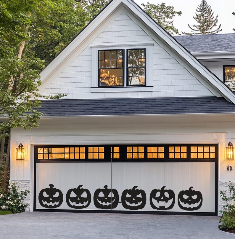 Puede incluir: Una puerta de garaje blanca con seis siluetas negras de calabazas talladas. La puerta del garaje forma parte de una casa blanca con tejado y molduras negras. La casa tiene una ventana y dos apliques, con tem&aacute;tica de Halloween.