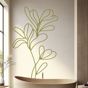 Op de afbeelding: Een houten badkuip met een groene lijntekening van een plant op de muur erachter.