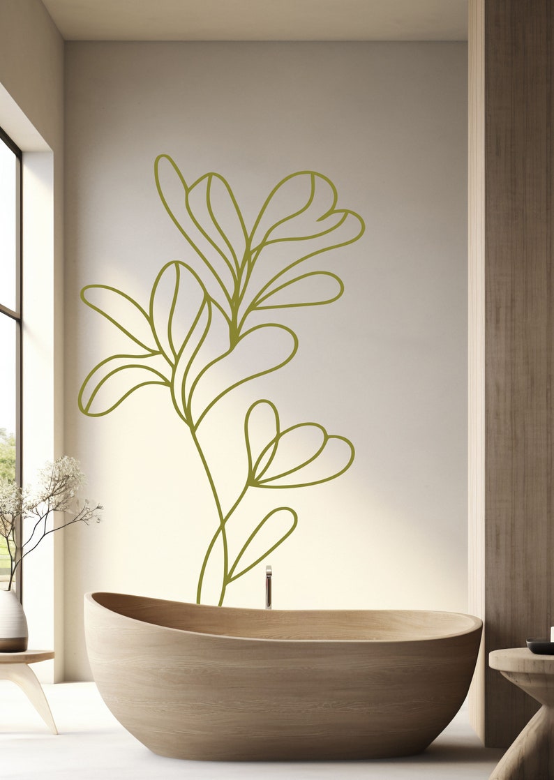 Op de afbeelding: Een houten badkuip met een groene lijntekening van een plant op de muur erachter.
