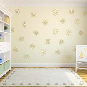 May include: A white bookshelf with a light wood top and a white rug with a floral pattern. The wall is a light yellow colour and has a pattern of gold daisy decals.