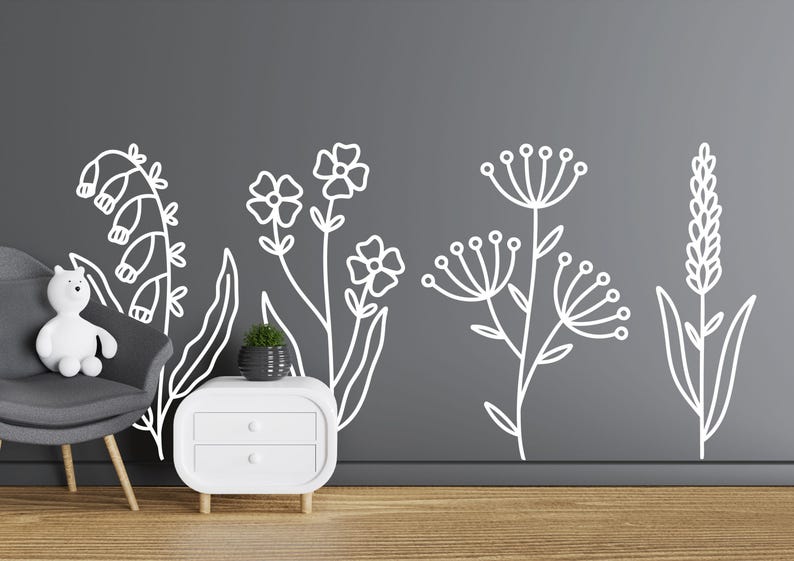 May include: White outline wall decals of various flowers and plants on a gray wall. The decals are in a row across the wall. There is a white nightstand with two drawers in the lower right corner of the image.