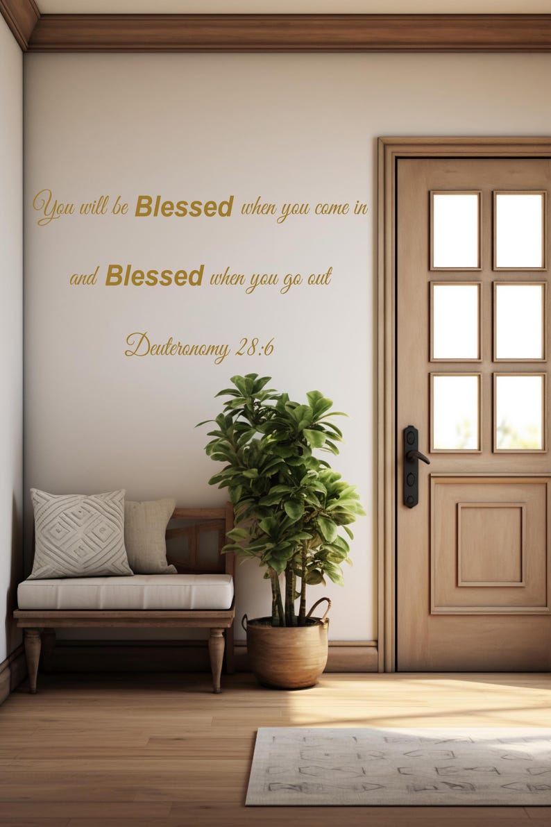 Pu&ograve; includere: Un adesivo da parete con il testo "You will be Blessed when you come in and Blessed when you go out Deuteronomy 28:6" in lettere dorate. L'adesivo &egrave; su una parete bianca con una porta in legno e una piccola panca con un cuscino.