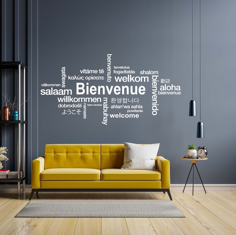 May include: A yellow sofa with a white word cloud on the wall behind it. The word cloud includes greetings in multiple languages, including "Welcome", "Bienvenue", and "Aloha".
