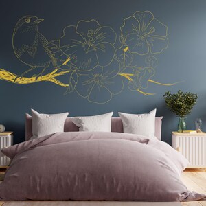 May include: A bedroom with a dark blue wall featuring a gold floral and bird design. The bed has a light pink duvet and white pillows.