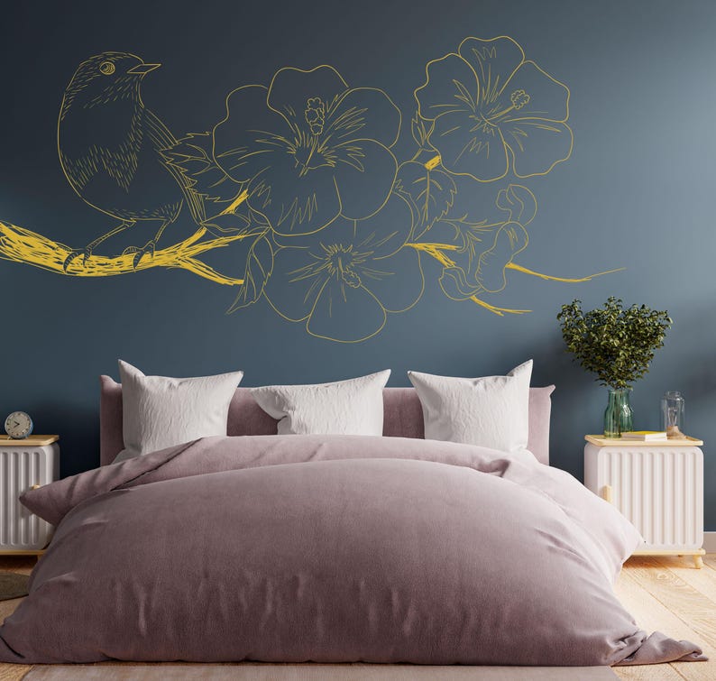 May include: A bedroom with a dark blue wall featuring a gold floral and bird design. The bed has a light pink duvet and white pillows.