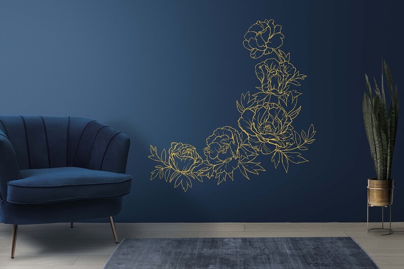 May include: A blue velvet armchair sits in front of a dark blue wall with a gold outline of a floral design.