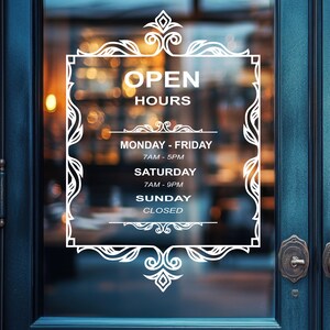 May include: White sign with ornate border on a glass door, displaying business hours: Monday - Friday 7AM - 5PM, Saturday 7AM - 9PM, Sunday Closed.