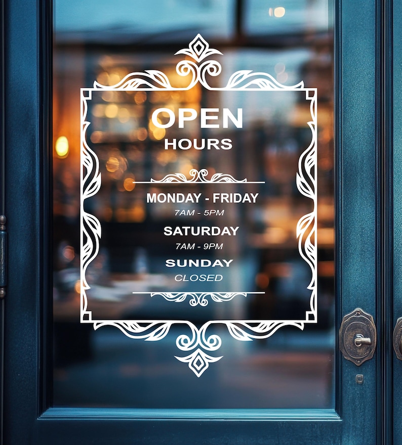 May include: White sign with ornate border on a glass door, displaying business hours: Monday - Friday 7AM - 5PM, Saturday 7AM - 9PM, Sunday Closed.