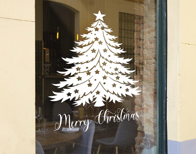 May include: White silhouette of a Christmas tree with stars on a storefront window. The text "Merry Christmas" is written below the tree.