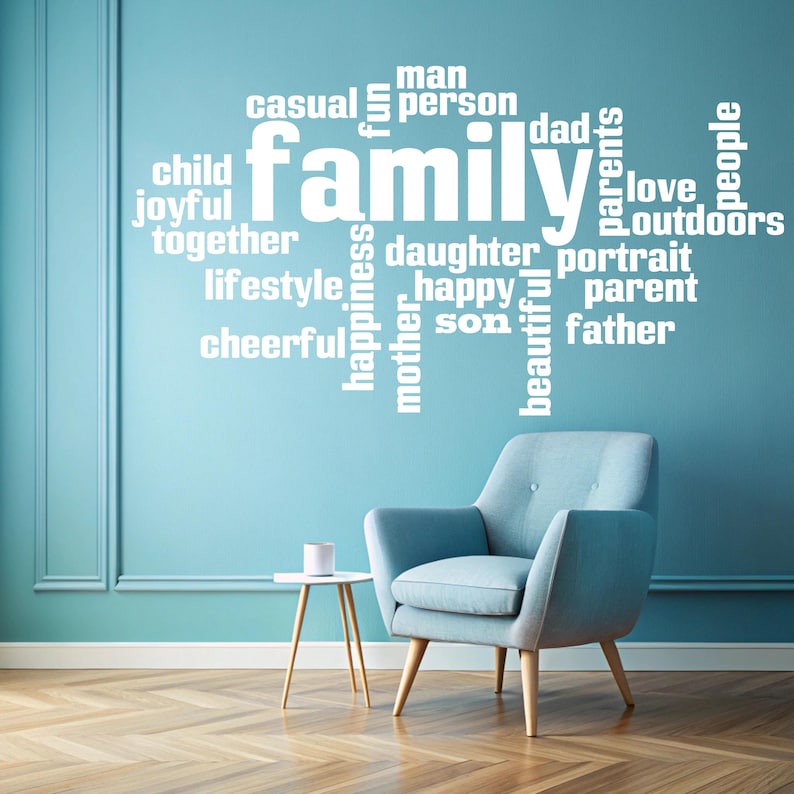 May include: A blue wall with a white word cloud that says "family" and includes words like "love", "happy", "joyful", "together", "daughter", "son", "mother", "father", "casual", "fun", "lifestyle", "cheerful", "person", "dad", "parents", "portrait", "outdoors", "people". A blue armchair and a small table are in front of the wall.