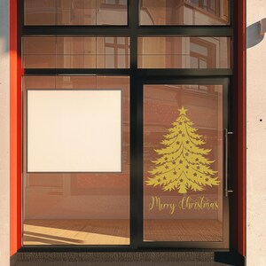 May include: A storefront window with a gold Christmas tree and the text "Merry Christmas" on the glass. The window is framed in black and the storefront is painted red.