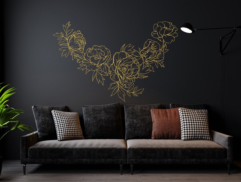May include: A black couch with three pillows, two black and white patterned pillows and one brown pillow, in front of a black wall with a gold floral design.