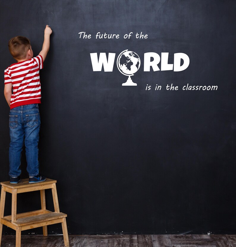 May include: A young boy stands on a wooden step stool and writes on a black chalkboard. The chalkboard says "The future of the WORLD is in the classroom" with a globe icon.
