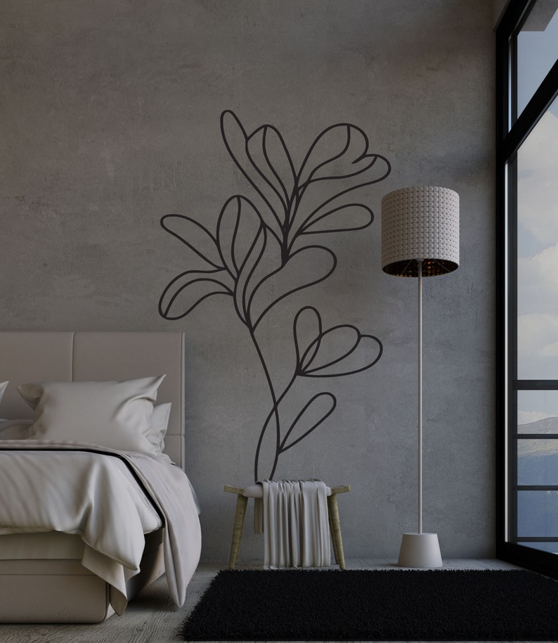 Op de afbeelding: Een slaapkamerinterieur met een bed, een kruk, een staande lamp en een zwart-witte abstracte bloemenmuursticker. De kamer heeft een groot raam met uitzicht op een bergketen.