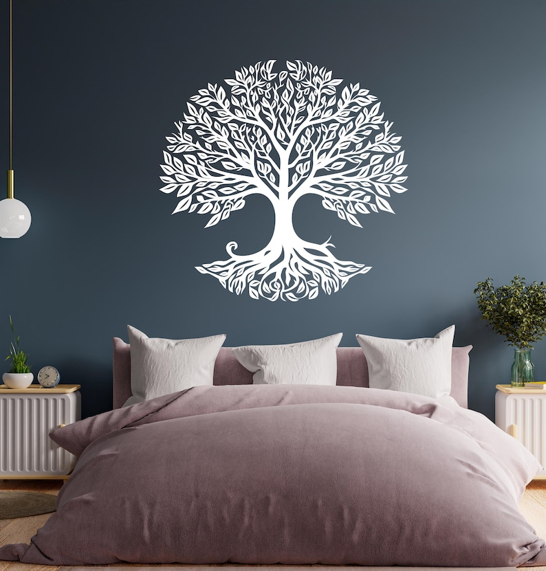 May include: A white tree of life wall decal with intricate branches and roots, displayed on a dark blue wall above a bed with a pink duvet cover.