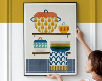 May include: A framed print of a kitchen still life featuring a collection of colourful ceramic pots and bowls on shelves. The print has a blue and white patterned background and a blue and yellow patterned fabric hanging below the shelves.