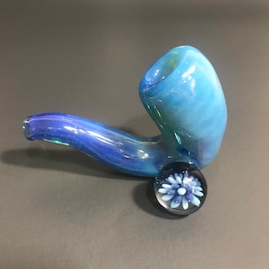 May include: A blue glass pipe with a swirl design and a blue and white glass flower accent.