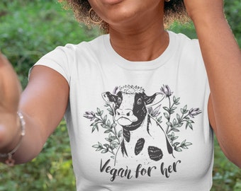 May include: White t-shirt featuring a black and white cow illustration and the text "Vegan for her".
