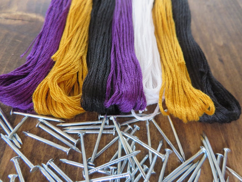 May include: Purple, yellow, black, white, and yellow embroidery floss spools with silver tacks.