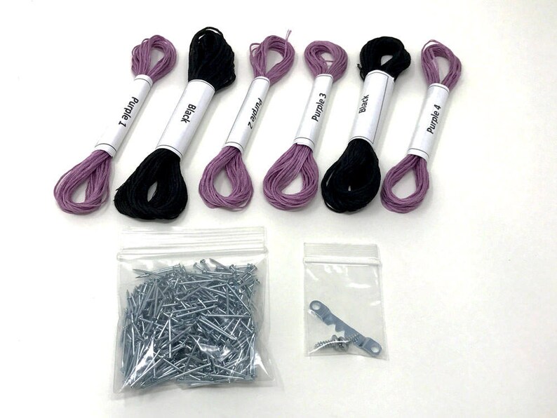 May include: A set of embroidery floss in purple and black colors, with labels that read "Purple 1", "Black", "Purple 2", "Purple 3", "Black", and "Purple 4". The set also includes a bag of silver tacks and a metal hook with two screws.