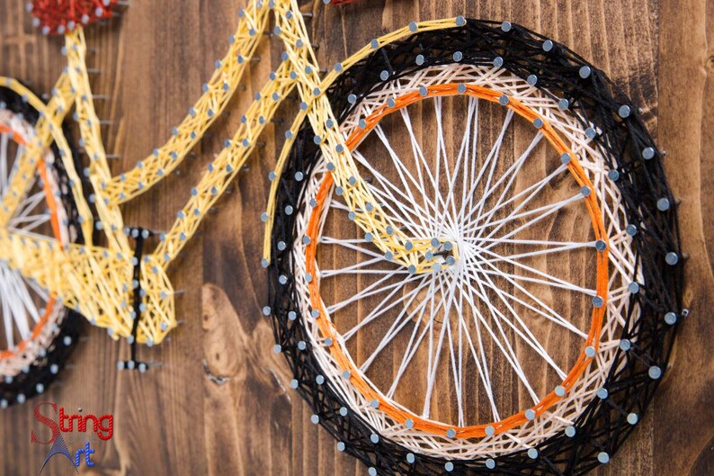 Puede incluir: Arte de hilo de una bicicleta amarilla con ruedas negras y naranjas sobre un fondo de madera.