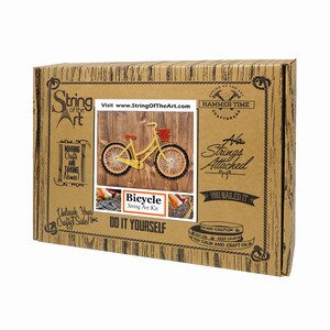 Puede incluir: Una caja de cart&oacute;n marr&oacute;n con un kit de arte de cuerda de bicicleta amarilla. La caja tiene el texto "String of the Art" y "Hammer Time Craft Brand". El kit incluye todos los materiales necesarios para crear un dise&ntilde;o de arte de cuerda de una bicicleta. La caja tambi&eacute;n tiene el texto "No Strings Attached" y "You Nailed It!"