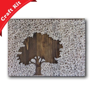May include: A string art craft kit featuring a tree design on a wooden base. The tree is outlined with white string and the background is a dark brown wood.