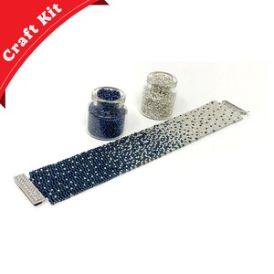 May include: A craft kit for making a beaded bracelet. The kit includes two jars of beads, one jar of dark blue beads and one jar of silver beads. The bracelet is made with a gradient of blue and silver beads.
