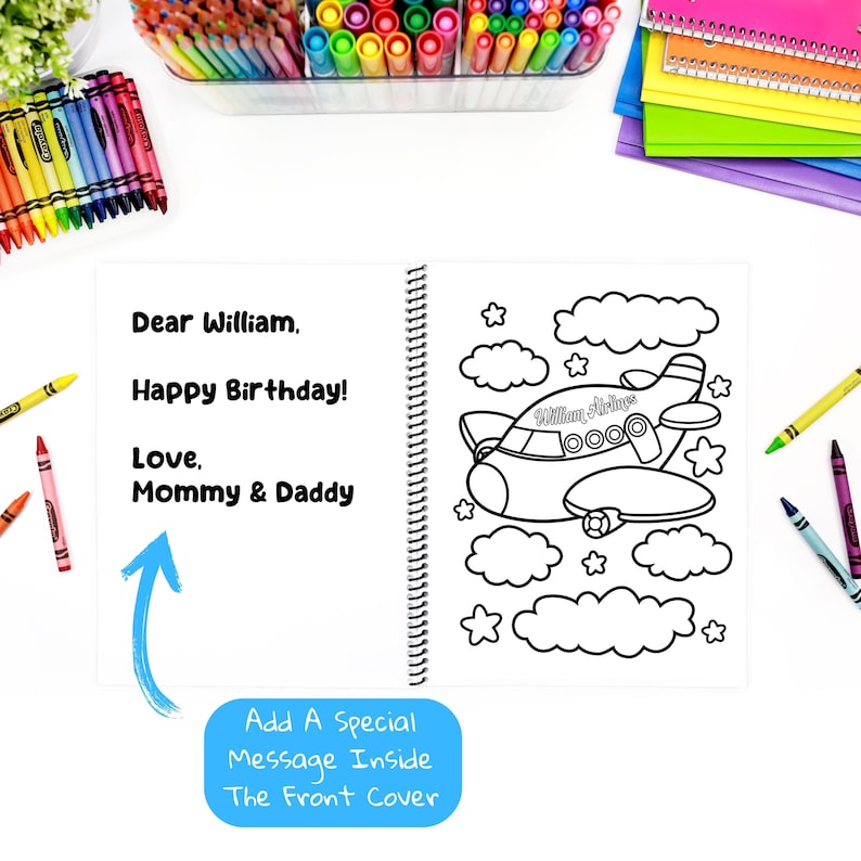 May include: An open spiral-bound coloring book featuring a black and white airplane illustration, clouds, and stars. The left page has the text: "Dear William, Happy Birthday! Love, Mommy & Daddy." A blue box says: "Add A Special Message Inside The Front Cover."