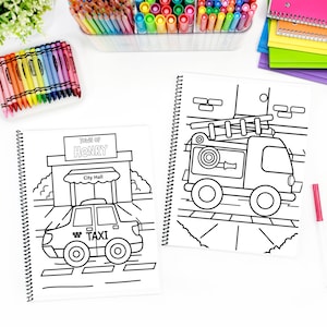 May include: Two spiral-bound colouring books with black and white illustrations. One shows a taxi in front of a city hall with "Town of Henry" and "City Hall" text. The other depicts a fire engine. Crayons and markers are visible.