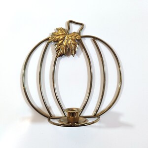 Peut inclure: Un bougeoir en métal doré en forme de citrouille. Le bougeoir présente un détail de feuille en haut et une petite coupelle pour accueillir une bougie. Le design est fait de fines tiges métalliques, créant un aspect ouvert et aéré. Le bougeoir est conçu pour l'automne.