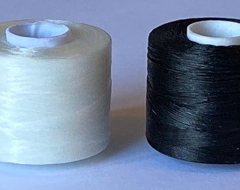 May include: Two spools of thread, one white and one black. The spools are wound with thread and have a white plastic center.