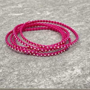 May include: A close-up of a pink rhinestone chain, with multiple strands of the chain coiled together.