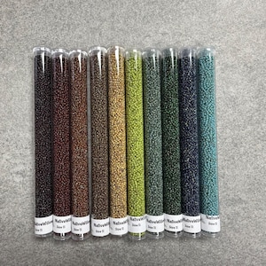 May include: Eleven clear tubes filled with small, round beads in various colours, including black, brown, green, and blue. Each tube has a white label with the text "Native Willow Size 11". The tubes are arranged vertically.