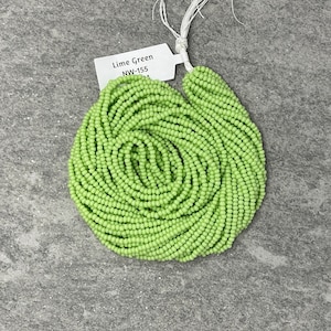 May include: A spool of lime green seed beads. The label reads "Lime Green NW-155".