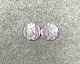 May include: Two round, marbled acrylic earring pendants. Each pendant is a circle with a hole at the top and bottom. The pendants have a swirling pattern of white, pink, and silver glitter.