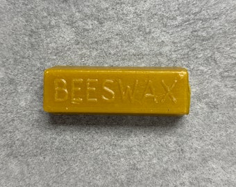 Peut inclure: Un bloc rectangulaire de cire d'abeille avec le mot "BEESWAX" en relief sur le dessus.