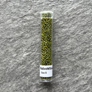 May include: A clear glass tube filled with small, green glass beads. The tube has a white label that reads "NativeWillow Size 11".