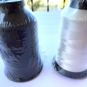 Puede incluir: Dos carretes de hilo, uno negro y uno blanco, envueltos en pl&aacute;stico transparente.