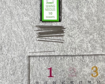 May include: A pack of 10 Pony sewing needles, size 10 sharps, with a green and white label featuring a horse logo. The needles are arranged in a pile on a gray surface next to a ruler.